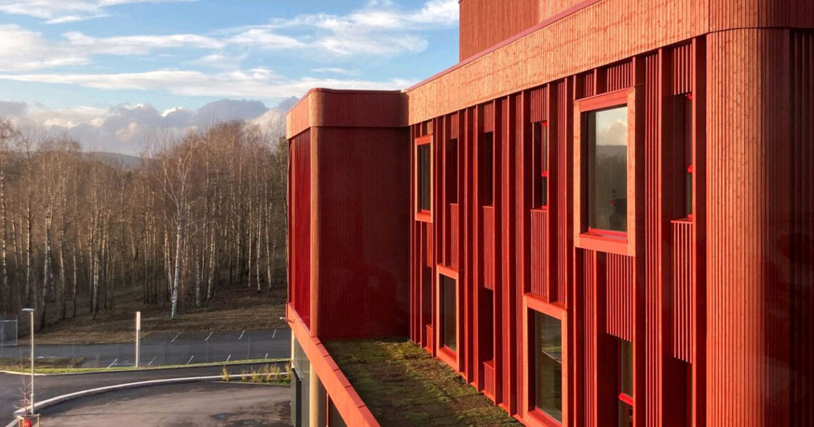 Moderne Schule in Lillestrøm mit roter Holzfassade, gebaut mit KNAPP-Produkten Ricon S und Megant, fotografiert von Nils Petter.